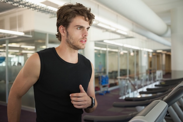 Fit man correr en la cinta de correr en el gimnasio