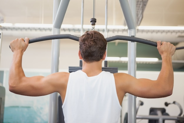 Fit man que usa la máquina de pesas para armas