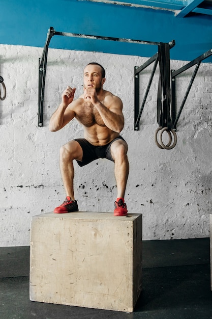 Fit Mann macht Box Jumps in einem Fitnessstudio