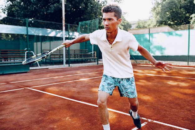 Fit Mann spielt morgens Tennis auf dem Tennisplatz