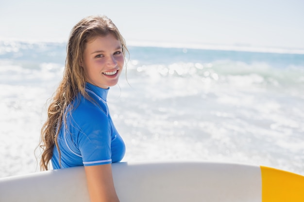 Fit menina surfista feliz na praia com sua prancha de surf