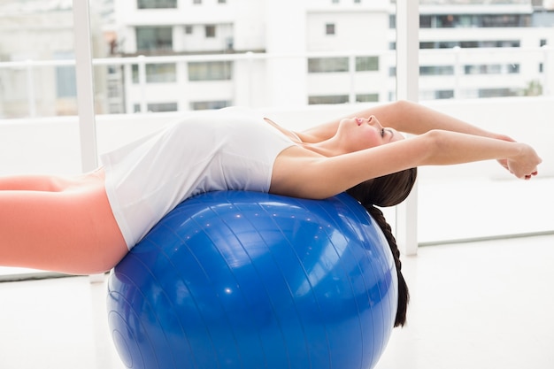 Foto fit morena alongamento em uma bola de exercício