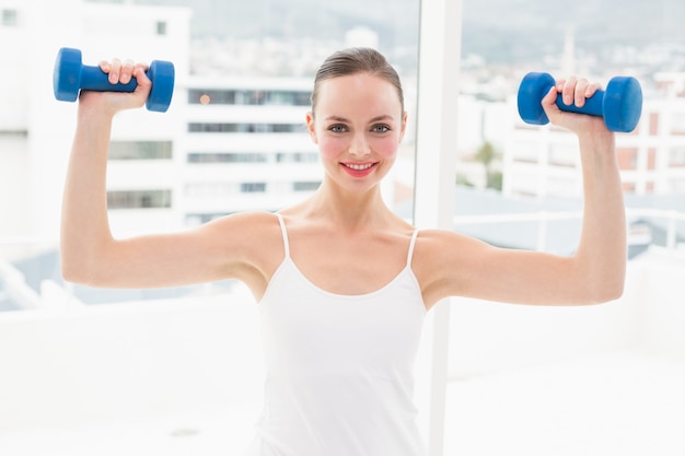 Fit morena segurando dumbbells azuis