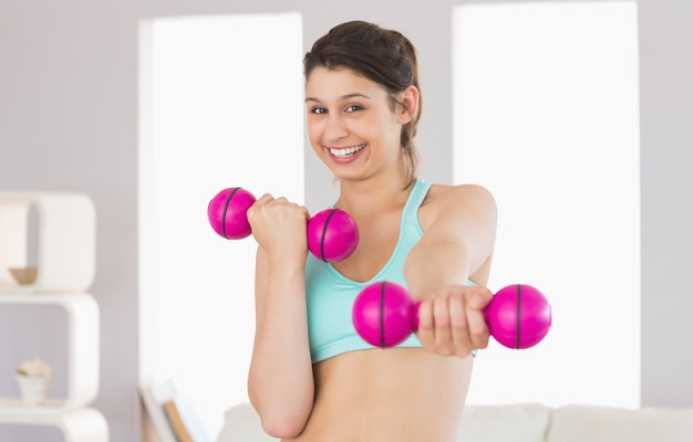 Fit morena segurando dumbbells rosa