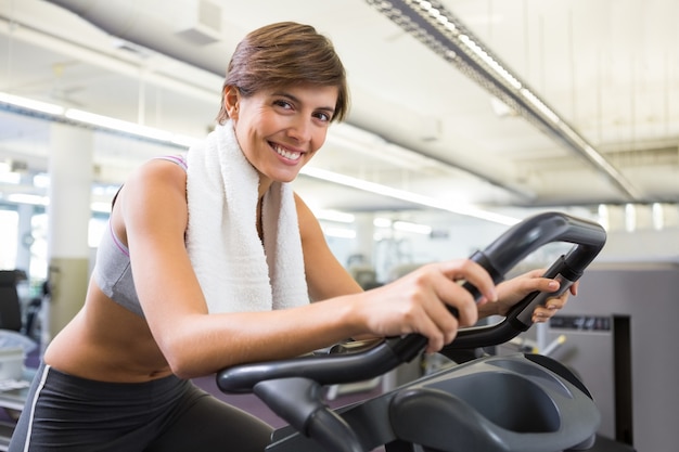 Fit morena sorridente trabalhando na bicicleta de exercício