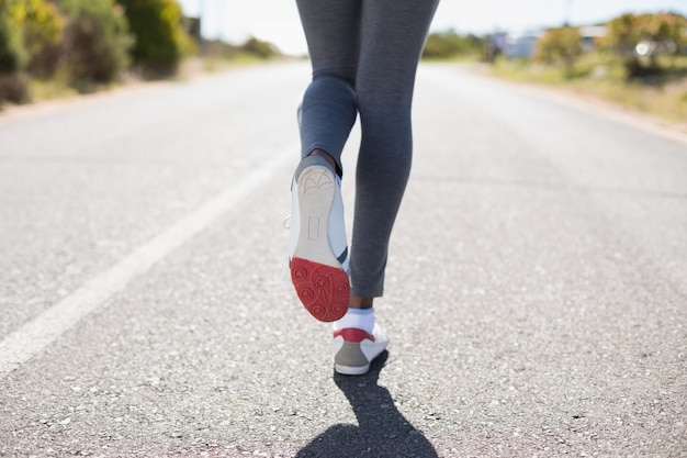 Fit mujer corriendo por la carretera abierta