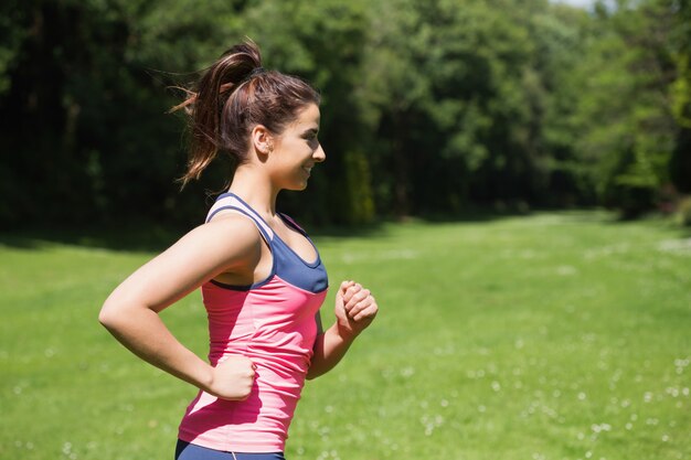 Fit mujer corriendo bajo el sol y sonriendo