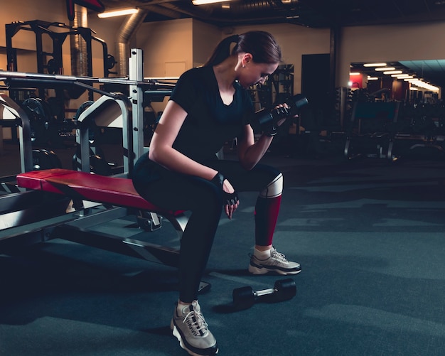 Fit mujer haciendo ejercicios de bíceps con pesas en el gimnasio