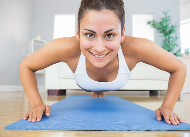 Fit mujer joven practicando ups en una estera de ejercicio azul