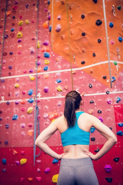 Fit mujer mirando a la pared de escalada