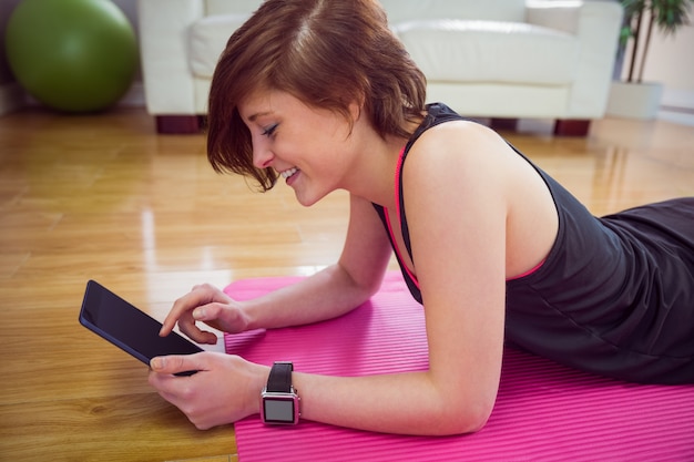 Fit mujer usando la pc de la tableta en la estera