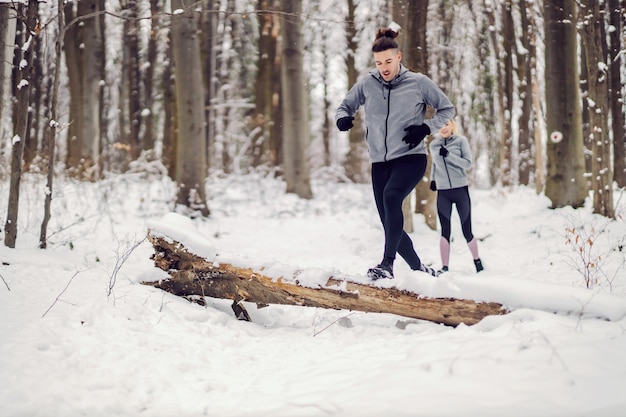 Fit Paarrennen im Wald am verschneiten Wintertag. Beziehung, gesunder Lebensstil, Erfolg