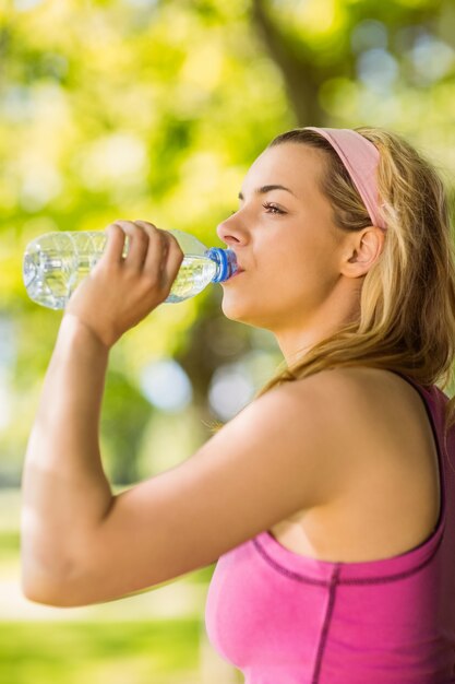 Fit rubia apoyada contra el árbol de agua potable