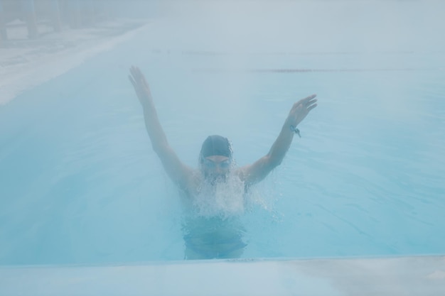 Fit Schwimmer männlich Training Schwimmen im offenen Winterschwimmbad mit Nebel Geothermisches Spa-Konzept im Freien
