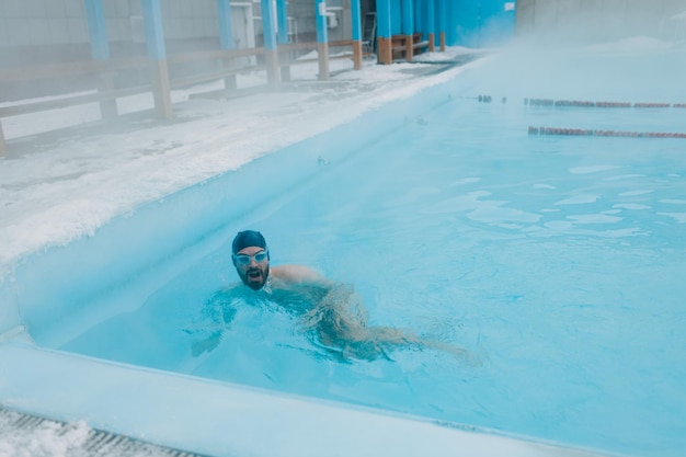 Fit Schwimmer männlich Training Schwimmen im offenen Winterschwimmbad mit Nebel Geothermisches Spa-Konzept im Freien