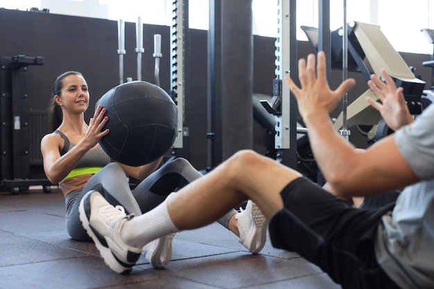 Fit und muskulöses Paar, das mit Medizinball im Fitnessstudio trainiert.