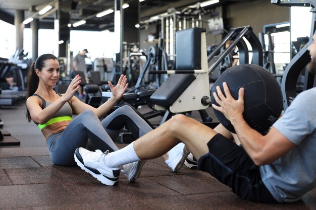 Fit und muskulöses Paar, das mit Medizinball im Fitnessstudio trainiert.