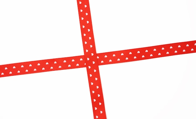 Fita de cetim vermelha cruzada sobre fundo branco, embrulho de presente