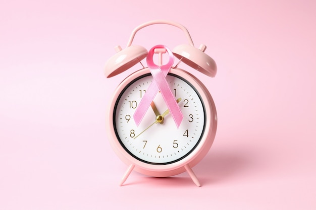 Fita de conscientização do câncer de mama e despertador em fundo rosa
