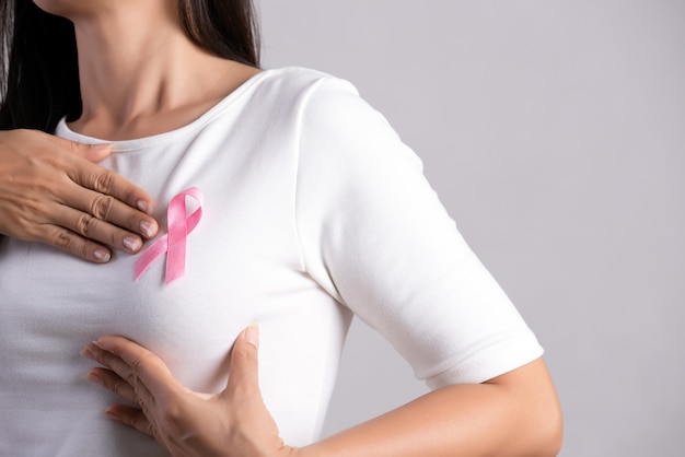 Foto fita de crachá rosa no peito de mulher para apoiar a causa do câncer de mama. conceito de saúde.