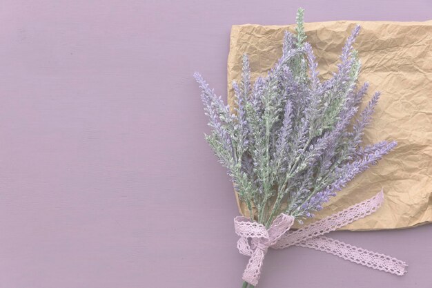 Foto fita de flores de lavanda com laço em fundo de madeira roxo perto de papel ecológico
