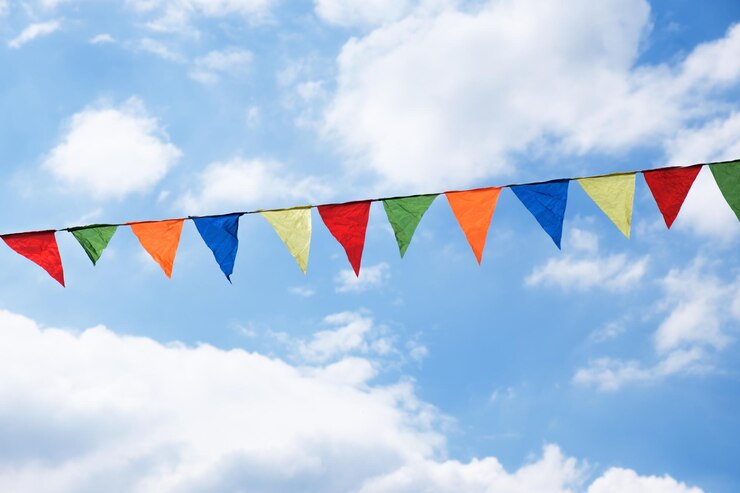 Fita festiva de bandeiras de triângulo multicoloridas nas nuvens brancas e fundo do céu azul