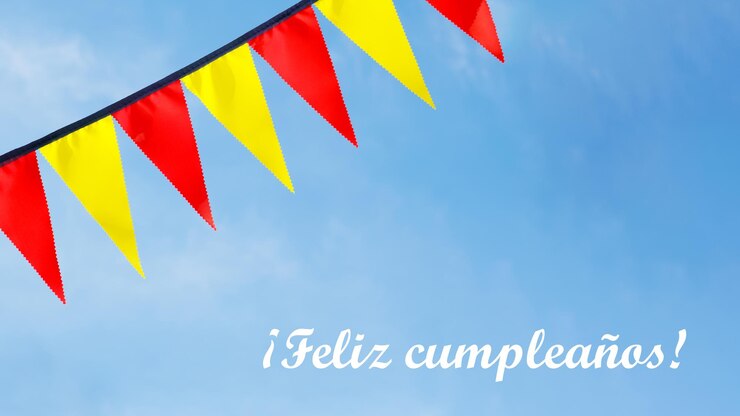 Foto fita festiva de sinalizadores de triângulo vermelho e amarelo no céu azul. feliz aniversário de inscrição em espanhol