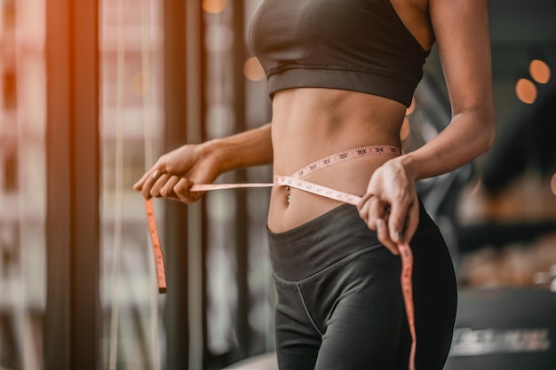 Fita jovem magro após uma dieta com acessório no ginásio desportivo como pano de fundo.