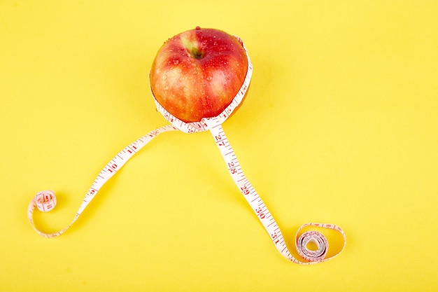 Fita métrica enrolada em torno de uma maçã vermelha