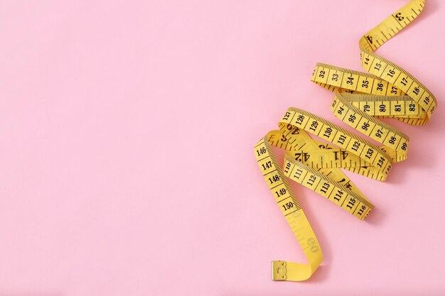 Foto fita métrica para pessoas obesas em um fundo rosa foco suave