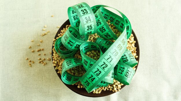 Fita métrica verde em um fundo de trigo sarraceno cru em um prato, conceito de dieta e saudável