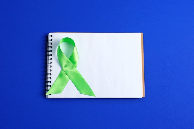 Foto fita verde clara e notebook aberto. consciência do linfoma do câncer de fígado. conceito de cuidados de saúde e medicina.