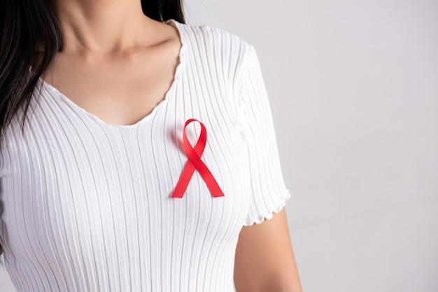 Fita vermelha distintivo no peito de mulher para apoiar o dia da aids. conceito de saúde.