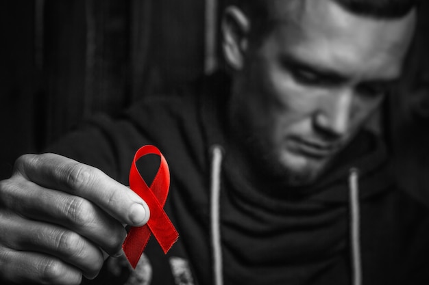 Fita vermelha na mão, símbolo da luta contra o HIV, AIDS. conceito de ajudar os necessitados. preto e branco.