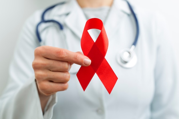 Fita vermelha nas mãos de um médico como um símbolo do dia mundial da Aids.