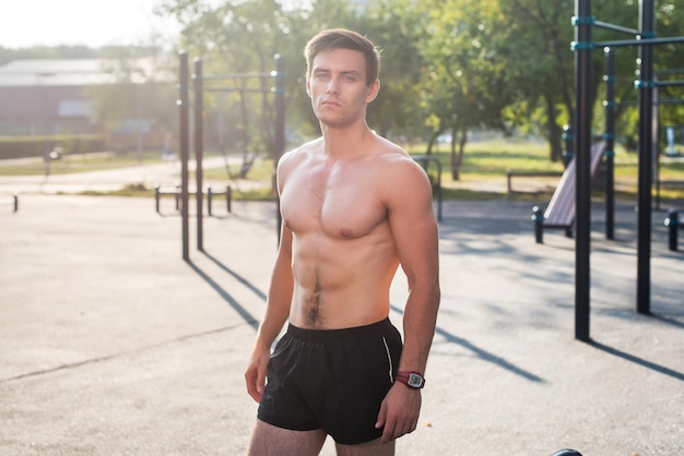 Fitnes hombre posando en la estación de fitness calle mostrando su cuerpo musculoso