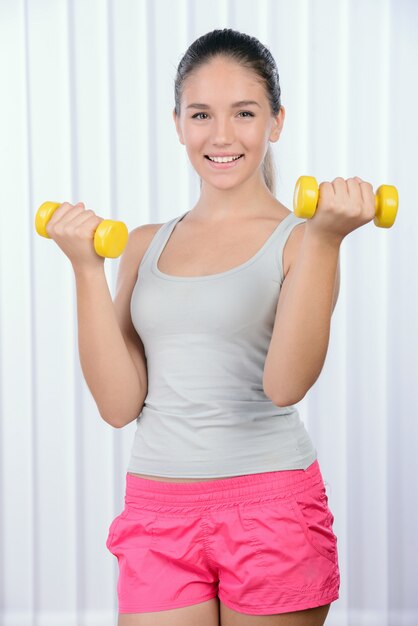 Fitness adolescente chica joven haciendo ejercicio con pesas.