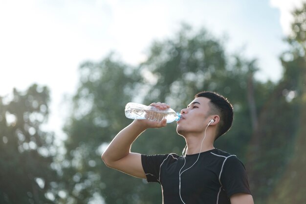 Fitness-Athlet junger Mann Trinkwasser nach dem Training im Park.