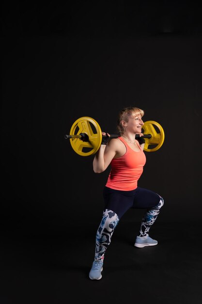 Fitness auf einer Stufenplattform mit einer Langhantel mit Hanteln Sport auf schwarzem Hintergrund