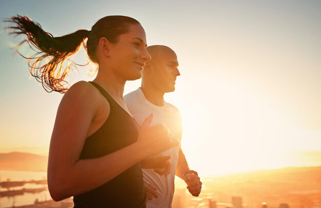 Fitness bei Sonnenaufgang und glückliches Paar beim gemeinsamen Laufen als Workout oder Morgengymnastik für Gesundheit und Wohlbefinden. Sportlerin und Läuferin laufen mit Sportlerin als Training in einer Stadt für Sport mit Energie