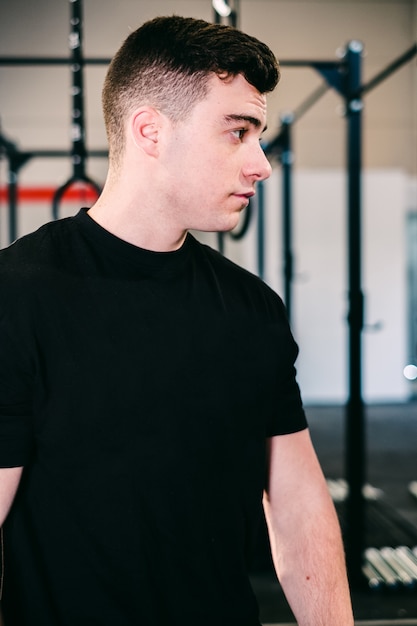 Fitness boy descansando después de hacer ejercicio apoyándose en el gimnasio