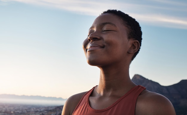 Fitness calma y respiración de mujer negra al aire libre en las montañas de la naturaleza y fondo de cielo azul para meditación de bienestar de yoga y energía zen Cara de niña respirando por la paz, la libertad y la atención plena