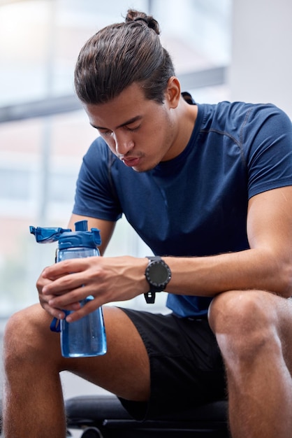 Foto fitness cansado ou homem na academia bebendo água respirando ou relaxando em um treino de exercício ou intervalo de treinamento cardiovascular fadiga bem-estar ou atleta de esportes saudável descansando no banco com garrafa de líquido