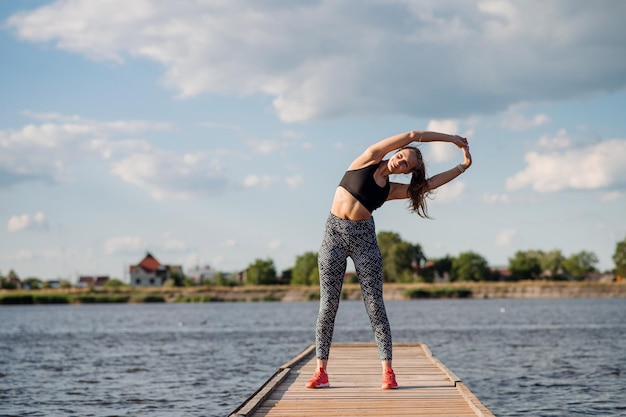 Fitness-Dame in Sportbekleidung, die Übungen am Pier macht