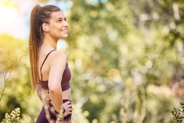 Fitness de bem-estar e mulher na natureza sorriem para desfrutar de ar fresco depois de correr treinamento de maratona e treino Motivação esportiva e garota feliz no parque para cardio de bem-estar zen e estilo de vida saudável