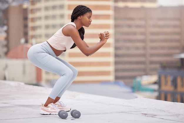 Fitness de mulher negra e treinamento de agachamento no telhado para exercícios de bem-estar, treino corporal e motivação de estilo de vida saudável, músculos de mulheres africanas ao ar livre e pernas fortes ou núcleo com mentalidade de foco