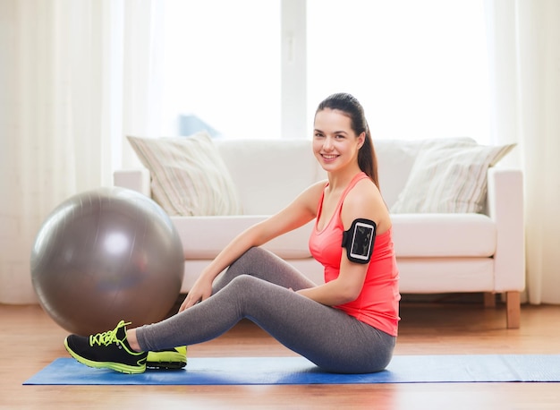 fitness, deporte en casa y concepto de dieta - adolescente sonriente con brazalete haciendo ejercicio en casa