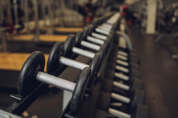 Foto fitness deporte ejercicio de levantamiento de pesas y concepto de culturismo cerca de pesas y equipos deportivos en el gimnasio