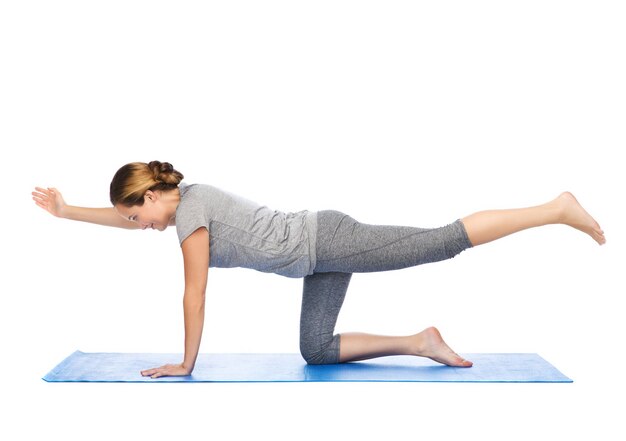 fitness, deporte, gente y concepto de estilo de vida saludable - mujer haciendo yoga en una mesa de equilibrio en la alfombra