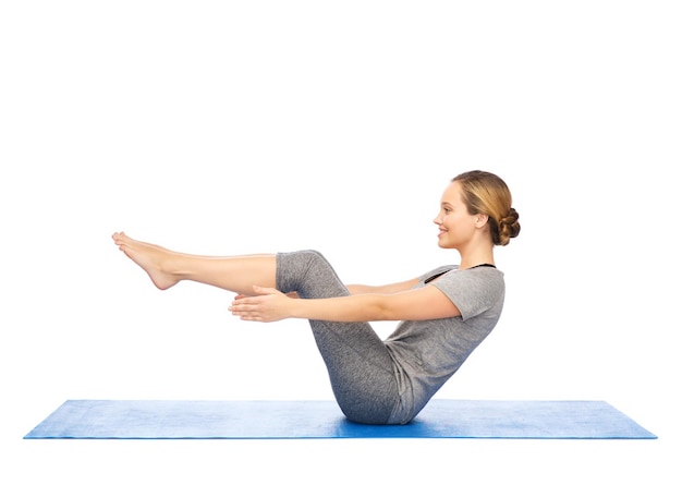 fitness, deporte, gente y concepto de estilo de vida saludable - mujer haciendo yoga en pose de medio bote en la alfombra